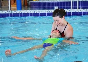 Women teaching boy how to swim